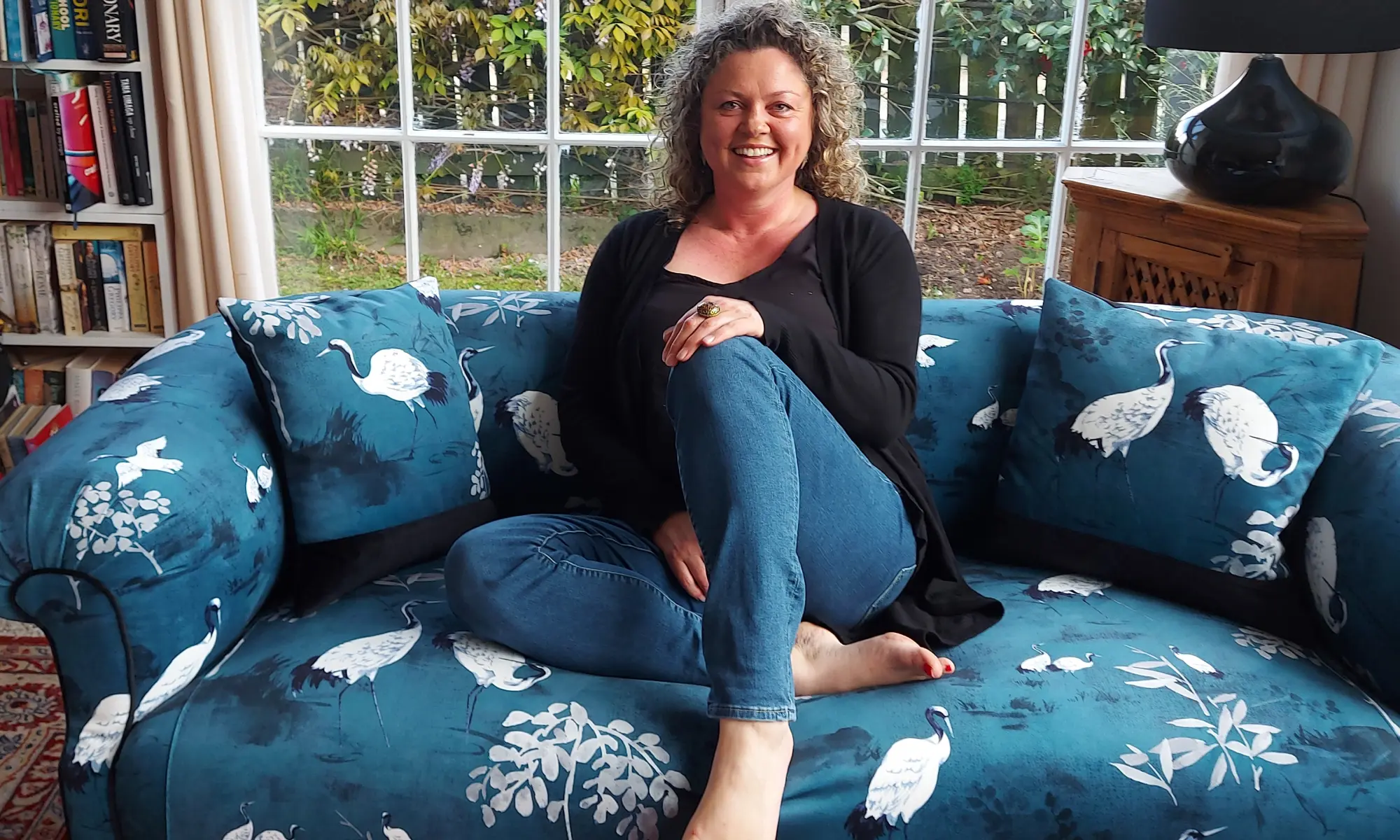 Lisa seated on a blue upholstered sofa at Boho Velvet Upholstery